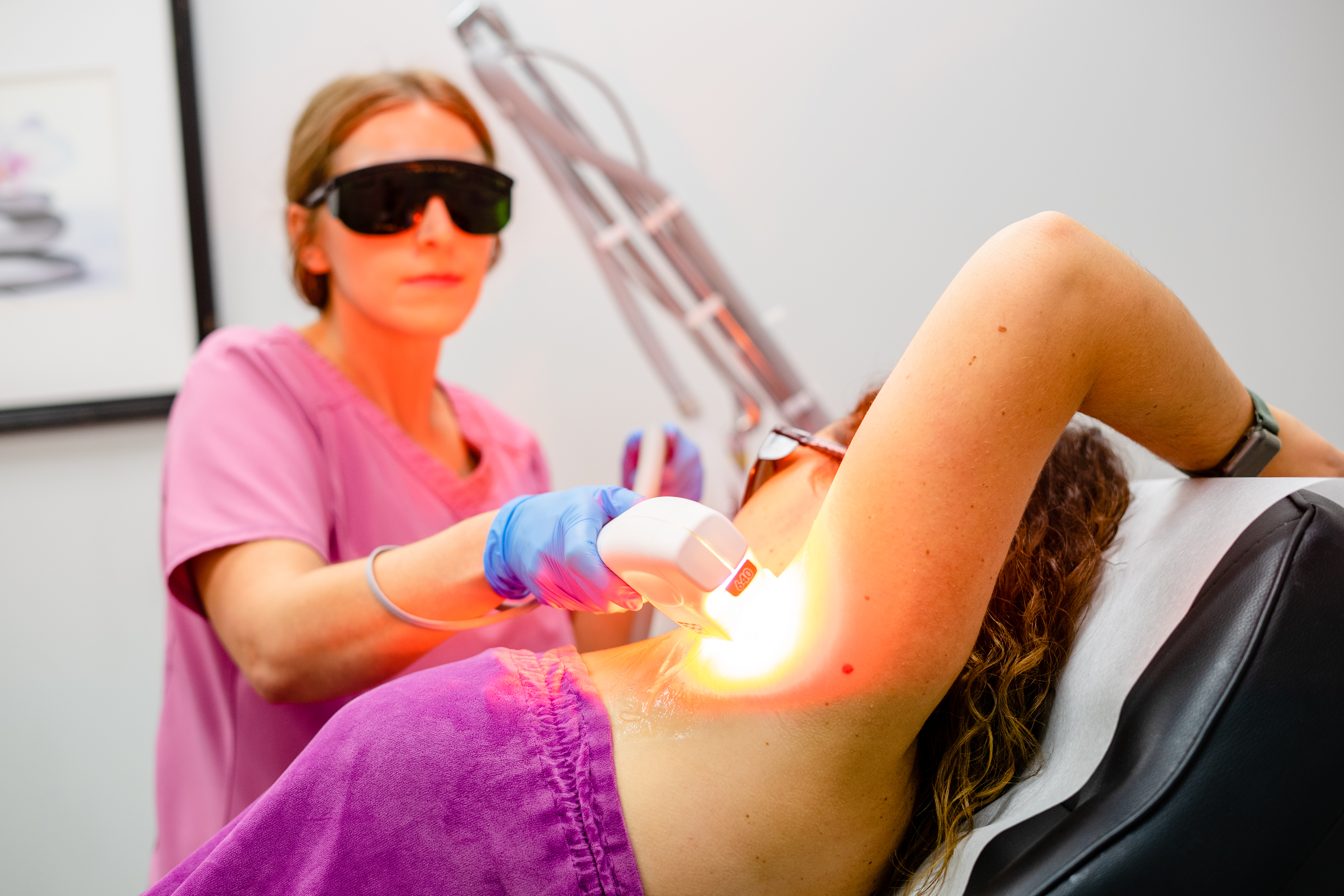 Aesthetician is performing laser hair removal on patient.